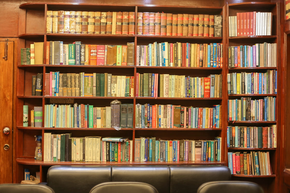 Shelves in the chambers holding law reports, statutes and reference volumes, with a bench along the foot of them.